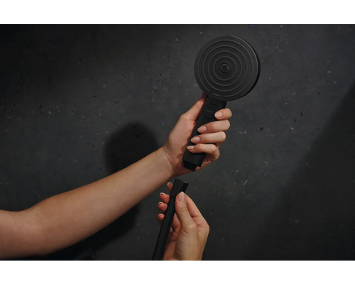 Eine Handbrause mit Brauseschlauch wird in der Hand gehalten.