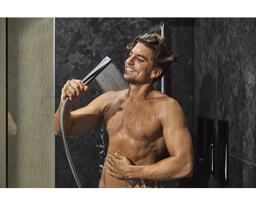 Mann benutzt eine Handbrause in einer Dusche mit dunklen Marmorfliesen