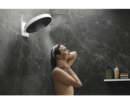 Frau duscht unter einer Kopfbrause in einem Badezimmer mit Marmorfliesen