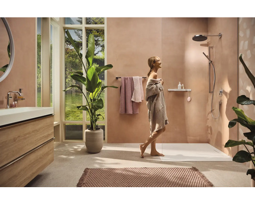 Modernes Badezimmer mit Dusche, Waschbeckenunterschrank, Handtüchern, Zimmerpflanzen und einer Frau im Bademantel