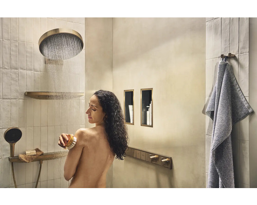 Badezimmer mit Dusche, Brausekopf, Handtuch und Frau, die sich mit einer Bürste den Rücken schrubbt.