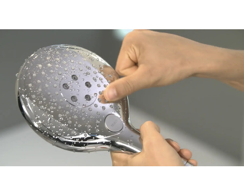 Handbrause mit Kalkablagerungen wird von einer Hand gereinigt.