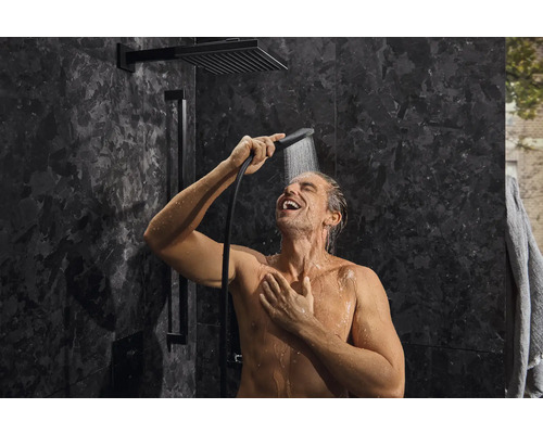 Mann unter Dusche mit Kopf- und Handbrause im Badezimmer