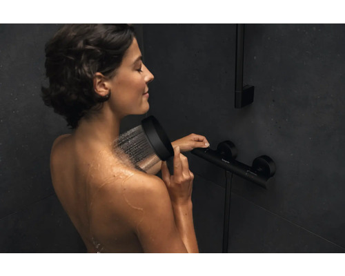 Femme sous la douchette dans la douche avec robinetterie de douche