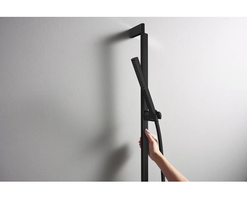 Schwarze Duschsäule mit Handbrause an einer Wand befestigt.
