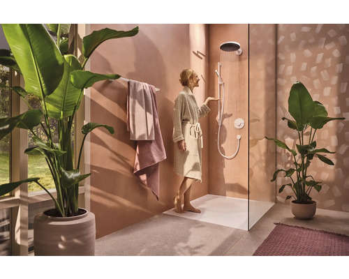 Helles Badezimmer mit Dusche, Handtüchern und Zimmerpflanzen für eine entspannende Atmosphäre.