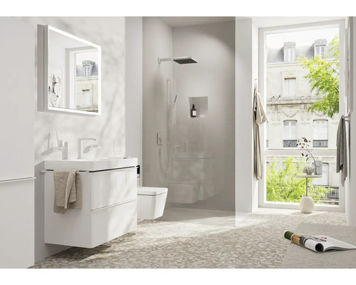 Helles Badezimmer mit Waschtisch, Spiegel, Dusche und Toilette.