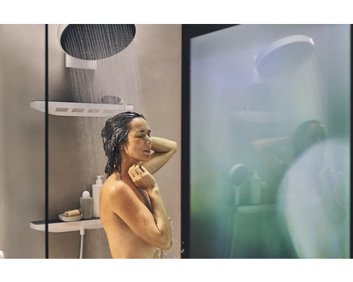 Frau duscht unter einer Kopfbrause mit Ablage im Badezimmer.