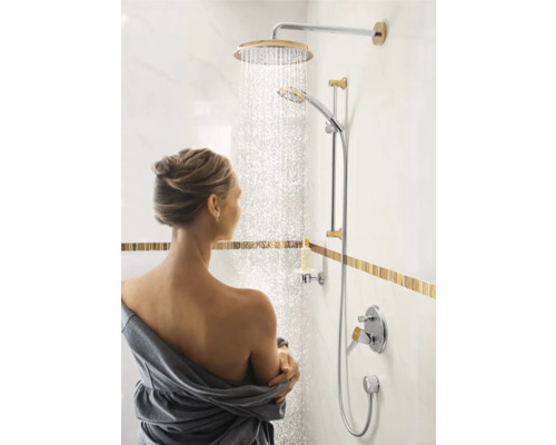 Frau unter einer Duschgarnitur mit Kopf- und Handbrause im Badezimmer.