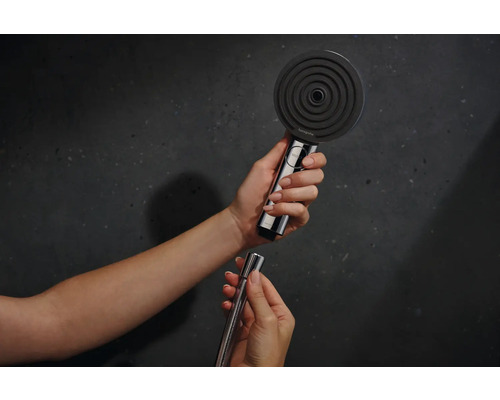 Frau verbindet Handbrause mit Duschschlauch