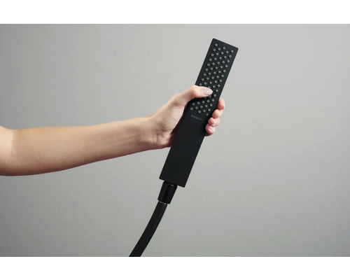 Eine Person hält einen schwarzen Handbrausekopf der Marke Hansgrohe.