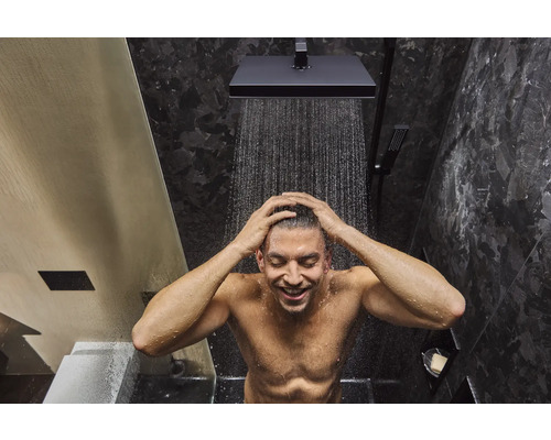 Mann duscht unter einer quadratischen Kopfbrause im Badezimmer