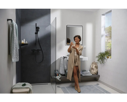 Salle de bains lumineuse avec douche, lavabo et une femme