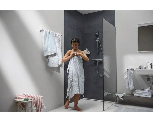 Helles Badezimmer mit Dusche, Waschbecken und Handtüchern