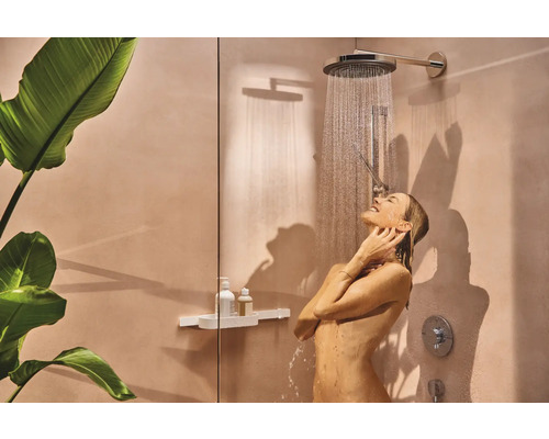 Frau unter einer Dusche mit Regenduschkopf in einem hellen Badezimmer