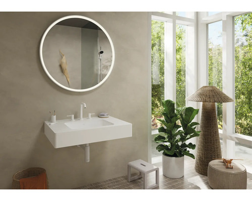 Modernes Badezimmer mit beleuchtetem Spiegel, Waschbecken und natürlichen Elementen für eine helle Atmosphäre.