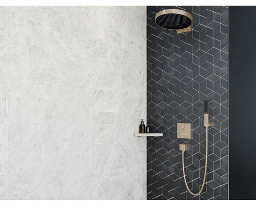 Badezimmer mit hellen Marmorfliesen, einer Ablage mit Kosmetikprodukten und einer Duschwand mit geometrischen Fliesen und Duscharmatur