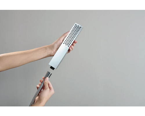 Hände verbinden einen rechteckigen Duschkopf mit einem Brauseschlauch.