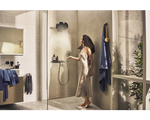 Helles Badezimmer mit Dusche, Waschbecken, Spiegel, Handtüchern und Frau unter der Dusche