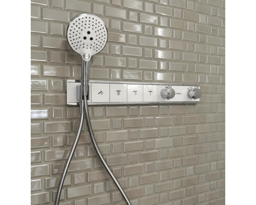 Système de douche apparent avec douchette sur un mur carrelé