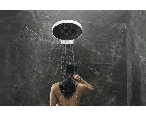 Frau unter einer Kopfbrause im Badezimmer mit Marmorwand