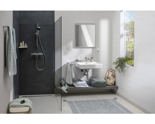 Helles Badezimmer mit Dusche, Waschbecken, Spiegel und Ablagefläche