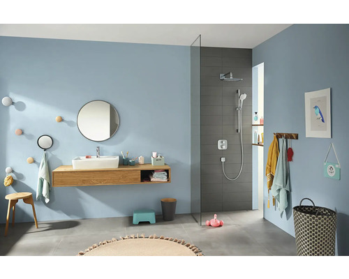 Salle de bain lumineuse avec lavabo, miroir, douche et divers accessoires.