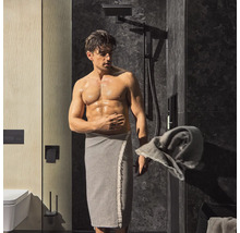 Salle de bains moderne avec carreaux de marbre foncés, douche et homme avec serviette