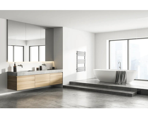 Badezimmer mit Doppelwaschbecken, Spiegel, Heizkörper und Badewanne auf einem Podest