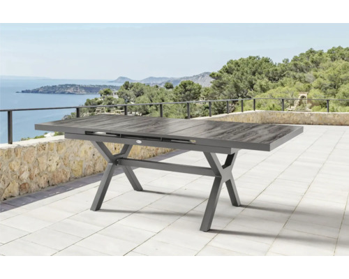 Table de jardin extensible avec cadre en forme de X sur une terrasse avec vue sur la mer