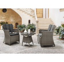 Ensemble de meubles de jardin avec deux fauteuils en rotin et une table ronde sur une terrasse pavée devant un bâtiment avec un escalier.