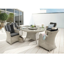 Scène de jardin avec table à manger ronde en rotin et quatre chaises assorties avec coussins