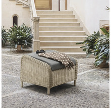 Geflochtener Hocker mit Kissen, Decke und Sonnenbrille auf einer Terrasse