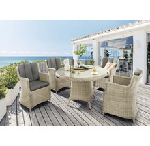 Salon de jardin avec table ronde et quatre fauteuils en osier sur une terrasse avec vue sur la mer