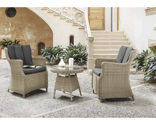 Fauteuil de jardin Destiny Luna Malaga 2 places 3 pces naturel chiné, 2 fauteuils + table, rotin synthétique + aluminium, y compris galettes d'assise Ensemble de mobilier de jardin avec deux fauteuils en osier, coussins gris et table ronde avec plateau en verre devant un bâtiment