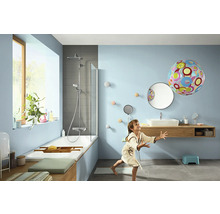 Salle de bain lumineuse avec baignoire, douche, lavabo et enfant jouant