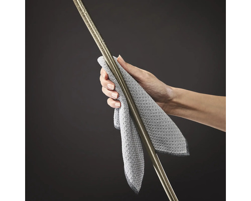 Une main essuie une barre métallique avec un chiffon de nettoyage