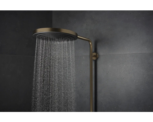 Messingfarbene Duscharmatur mit laufendem Wasser vor dunklem Hintergrund.