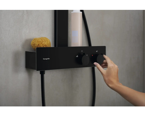 Schwarze Aufputz-Duscharmatur mit Ablage und Hand, die den Temperaturregler bedient