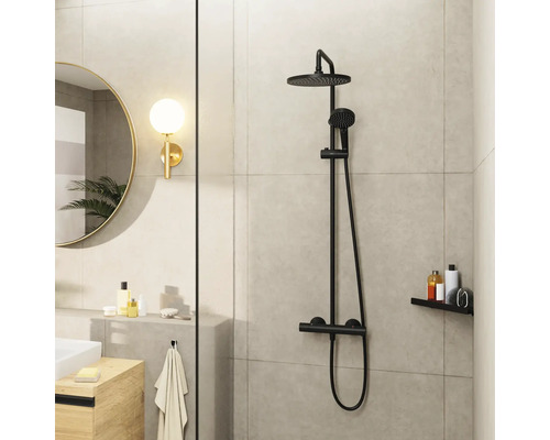 Salle de bain avec robinetterie de douche noire, miroir rond et étagère