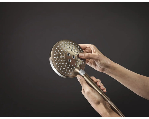 Une douchette à main est tenue dans la main.