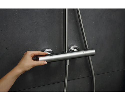 Hand bedient eine Duscharmatur mit Thermostat an einer Wand