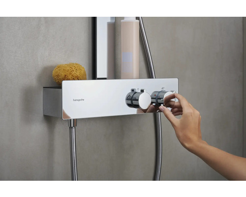 Robinet thermostatique apparent dans la salle de bains avec main, éponge et articles de douche sur l''étagère