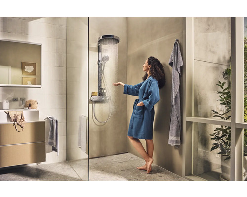 Salle de bains lumineuse avec douche, lavabo et une femme en peignoir touchant l''eau