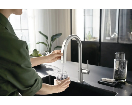 Küchenszene mit Wasserhahn, aus dem Wasser in ein Glas läuft