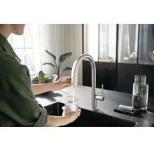 Frau befüllt Glas mit Wasserhahn in einer Küche