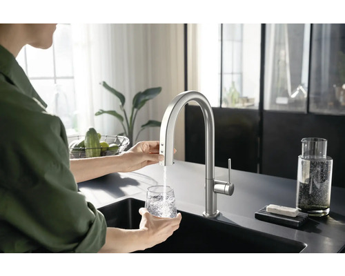 Frau befüllt Glas mit Wasserhahn in einer Küche