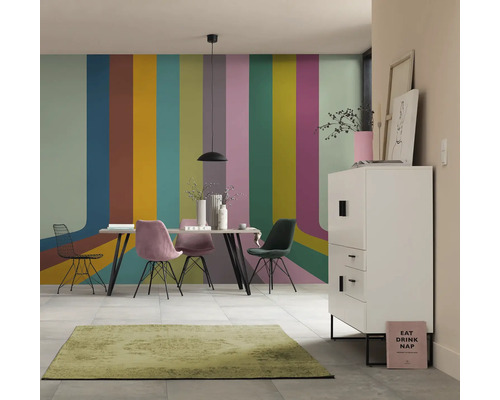 Salle à manger avec table, chaises, buffet et tapis devant un mur à rayures