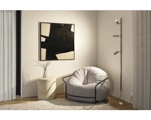 Wohnzimmerszene mit Sessel, Stehlampe und Kunstwerk an der Wand