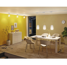 Salle à manger avec table à manger, chaises, buffet, spots de plafond et suspensions.